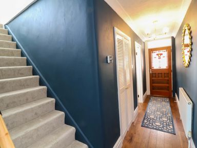 A hallway with stairs, door, and rug at Combe View in Ilfracombe