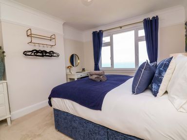 A bedroom with a bed, pillows, and a clothes rack at Combe View in Ilfracombe