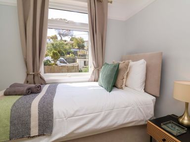 A bedroom with a bed and window at Combe View in Ilfracombe