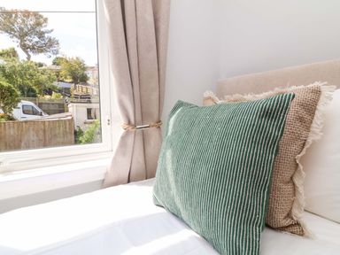 A bedroom with a window and cushions at Combe View Ilfracombe