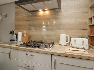 A kitchen countertop with a gas stove kettle toaster coffee machine and wooden utensils at Mon in Troutbeck Bridge