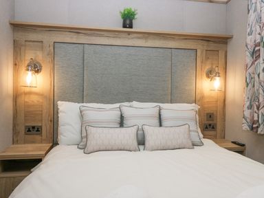 A bed with multiple pillows and a wooden headboard with lights on each side at Mon in Troutbeck Bridge