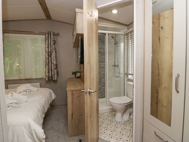 A bedroom with a bed and towels next to a bathroom with a shower and toilet at Mon in Troutbeck Bridge