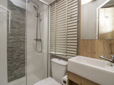 A bathroom with a shower enclosure stone tile wall toilet with paper holder and a sink with a mirror above at Mon in Troutbeck Bridge