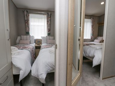 A bedroom with two single beds separated by a nightstand and a mirror on the wardrobe door at Mon in Troutbeck Bridge