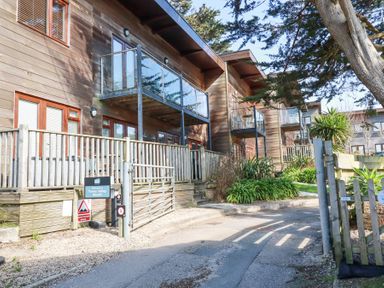 A row of wooden houses with balconies and glass railings at Towan Valley Resort in Porthtowan