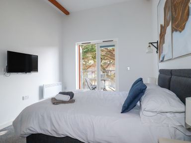 A bedroom with a bed pillows and folded towels near a window with chairs and a table outside at Tincroft in Porthtowan
