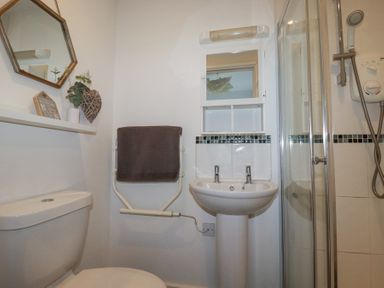 A bathroom with a toilet sink shower mirror towel and decorations at Tincroft in Porthtowan