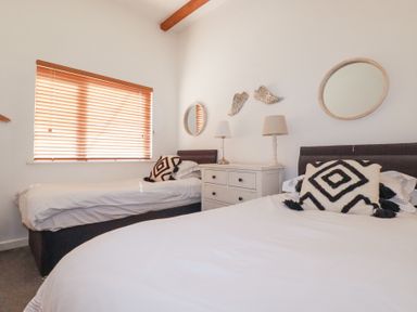 A bedroom with two beds bedside table lamps and mirrors at Tincroft in Porthtowan
