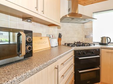 A kitchen countertop with a microwave bread box toaster stove and kettle at Lodge 3 At Pound Farm in Crook near Kendal