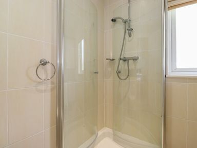 A bathroom shower enclosure with glass doors and a showerhead at Lodge 3 At Pound Farm in Crook near Kendal