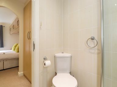A bathroom with a toilet and a towel ring next to a bedroom with a bed and storage cupboards at Lodge 3 At Pound Farm in Crook near Kendal