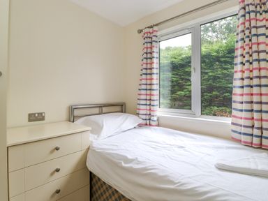 A small bedroom with a single bed and striped curtains at Lodge 3 At Pound Farm in Crook near Kendal