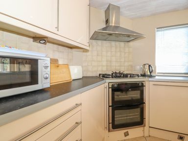 A kitchen with a microwave, bread bin, gas stove, double oven, kettle, and window at Lodge 7 At Pound Farm in Crook near Kendal