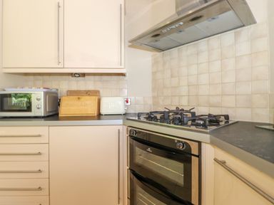 A kitchen corner with a microwave, bread box, toaster, gas stove, oven, and cream-colored cabinets at Lodge 7 At Pound Farm Crook near Kendal