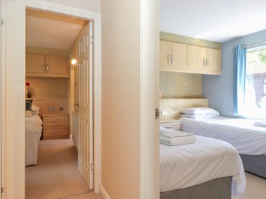 Two bedrooms each with twin beds bedside tables and overhead cabinets at Lodge 7 At Pound Farm Crook near Kendal