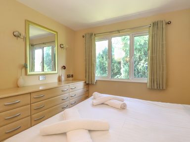 A bedroom with a bed with rolled towels a dresser with two vases and a mirror and a window with curtains at Lodge 7 At Pound Farm Crook near Kendal