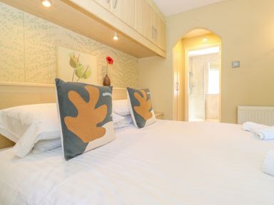 A bedroom with bed pillows a flower in a vase and an ensuite bathroom at Lodge 7 At Pound Farm in Crook near Kendal