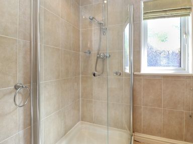 A bathroom shower with glass door and tiled walls near a window at Lodge 7 At Pound Farm Crook near Kendal