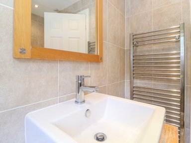 A bathroom sink with a faucet a wooden framed mirror and a chrome towel radiator at Lodge 7 At Pound Farm in Crook near Kendal