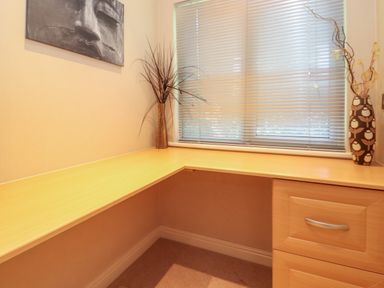 A corner desk with two vases of dried plants under a window with blinds and a wall art of a face at Lodge 7 At Pound Farm Crook near Kendal