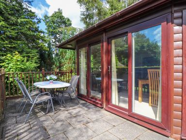 An outdoor patio with a round table and four chairs near glass doors at Lodge 7 At Pound Farm in Crook near Kendal