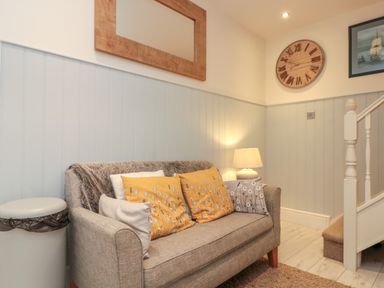 A seating area with a sofa and cushions next to a staircase and a lamp at Little Gem in Whitby