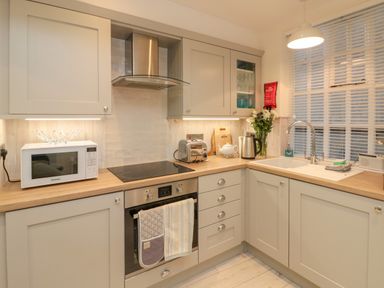A kitchen with microwave toaster oven kettle sink and cabinets at Little Gem in Whitby