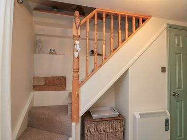 A stairway with wooden railing carpeted steps a wicker basket a white tray and a green door at Little Gem in Whitby
