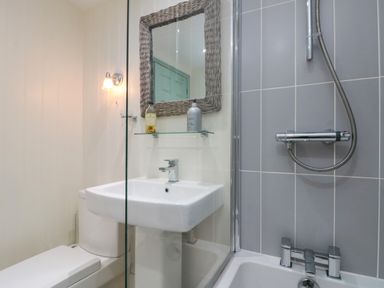 A bathroom with a toilet sink mirror and shower at Little Gem in Whitby