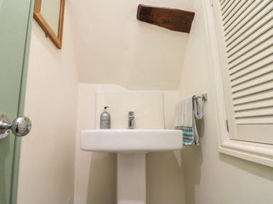 A small bathroom with a pedestal sink soap dispenser towel and mirror at Little Gem in Whitby
