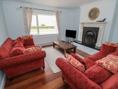 A living room with red sofas wooden coffee table and a fireplace at Cois Leice Cushlecka near Mulranny County Mayo
