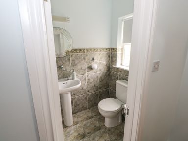 A small bathroom with a toilet sink mirror and window at Cois Leice Cushlecka near Mulranny County Mayo