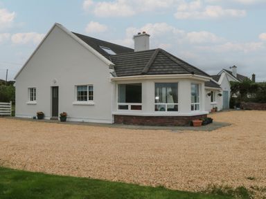 An exterior view of a white house with windows a gravel driveway and some potted plants at Cois Leice in Cushlecka near Mulranny County Mayo