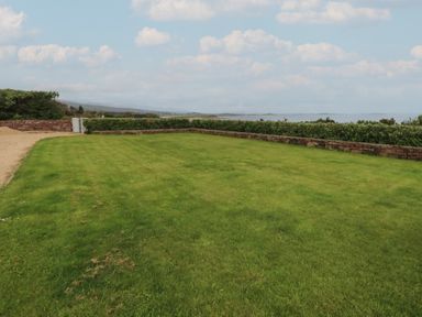 A grassy lawn with a stone wall and hedge overlooking the sea at Cois Leice in Cushlecka near Mulranny County Mayo