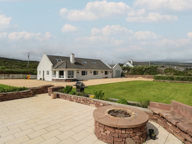 A house with a stone fire pit and bench in a garden with a lawn at Cois Leice Cushlecka near Mulranny County Mayo