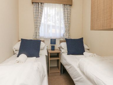 A bedroom with two single beds separated by a nightstand with a lamp at 23 Manleigh Park in Combe Martin