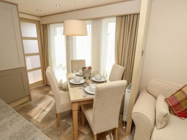 A dining area with a table set for four and beige chairs next to a sofa at The Boathouse in East Wittering