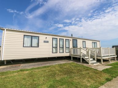 An exterior view of a white mobile home with windows and a porch with stairs at The Boathouse in East Wittering
