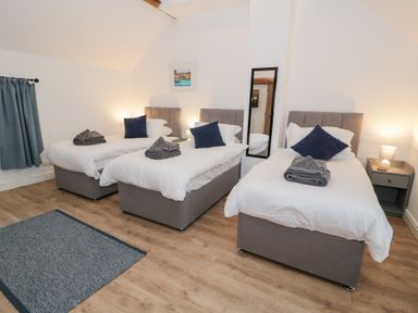 A bedroom with three beds and a mirror at Y Stabl in Cerrigydrudion