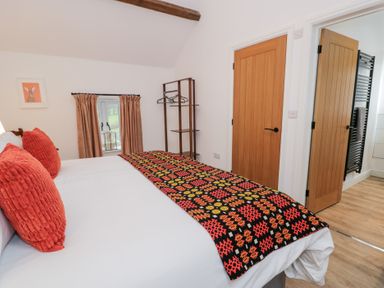 A bedroom with a bed and a clothes rack at Y Stabl in Cerrigydrudion