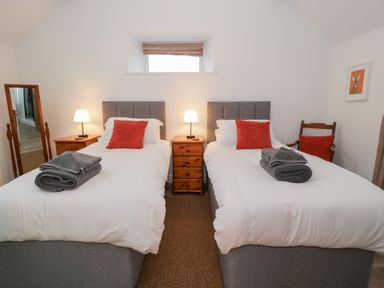 A bedroom with two beds and a nightstand at Y Stabl in Cerrigydrudion