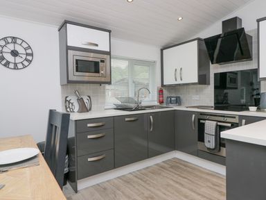 A kitchen with a microwave oven built into cabinetry a sink with a dish rack and a stove with an oven and a hood at Don's Lodge Grasmere 3 White Cross Bay near Windermere