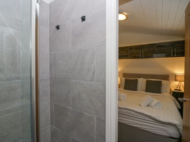 A bedroom with a bed and towels on it as seen from a bathroom with gray tiled walls at Don's Lodge in Grasmere 3 White Cross Bay near Windermere