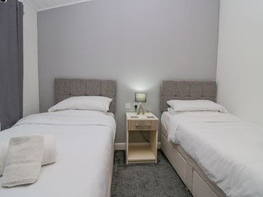 A bedroom with two single beds separated by a nightstand with a lamp at Don's Lodge Grasmere 3 White Cross Bay near Windermere