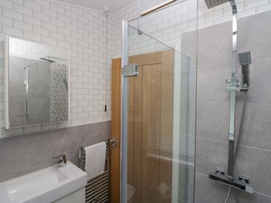A bathroom with a sink, mirror, towel rail, glass shower enclosure, and shower fixtures at Don's Lodge in Grasmere 3 White Cross Bay near Windermere