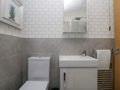 A bathroom with a toilet sink mirror shower and towel rack at Dons Lodge Grasmere 3 White Cross Bay near Windermere