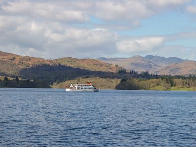 A boat on a lake with hills and mountains in the background at Don's Lodge in Grasmere 3 White Cross Bay near Windermere