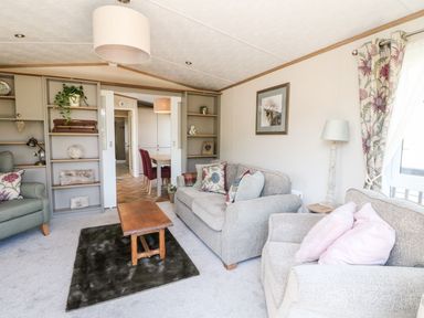 A living room with two armchairs a sofa coffee table and built in shelves at Saorsa in St Fillans