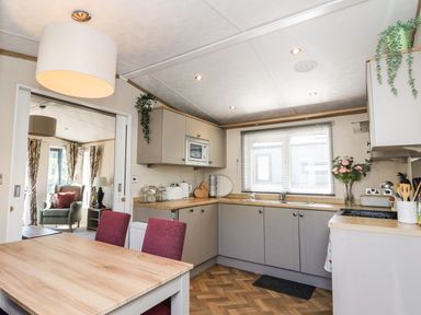 A kitchen with grey cabinets and a wooden dining table with red chairs at Saorsa in St Fillans